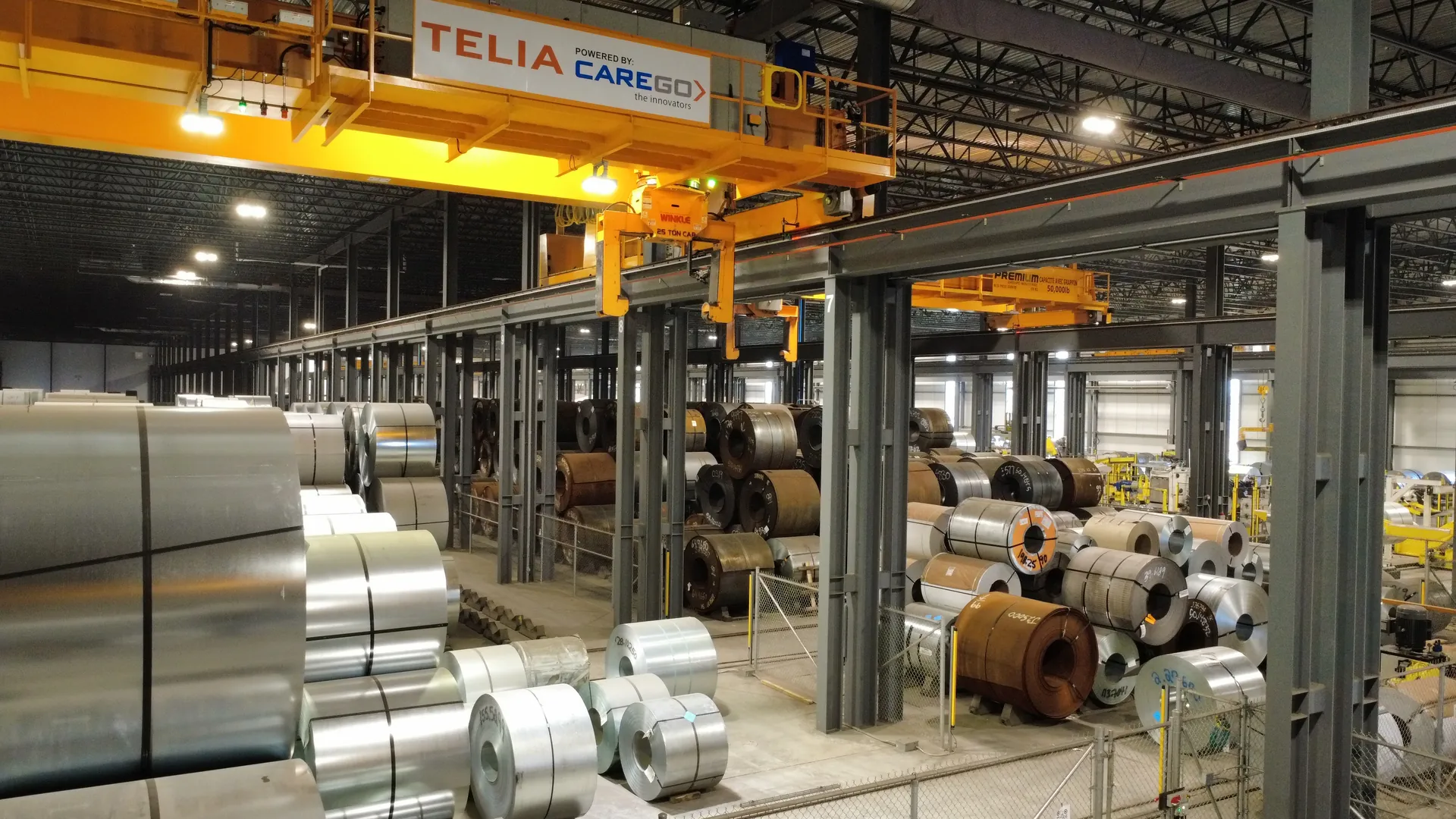 Luftaufnahme entlang einer Lagerhalle für Coils zwischen zwei Produktionshallen